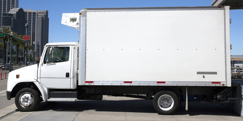 Refrigerated delivery truck backed up to warehouse loading dock.