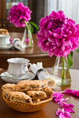 White cup of tea and biscuits and peony