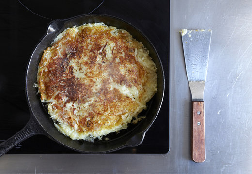 Hashbrowns in a cast iron pan with a spatula.