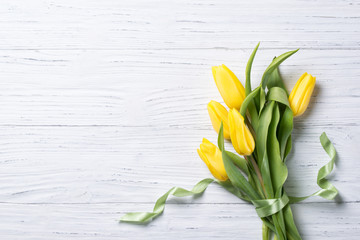 Yellow tulips bouquet on wooden background, top view with copy space