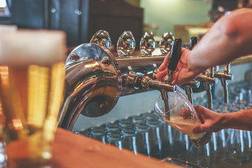 Two  Glasses of Beer on a bar table.  Focus on Beer Tap and bartender