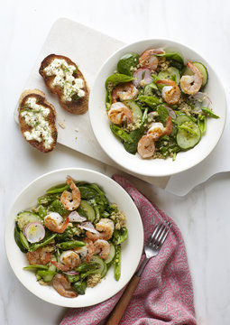 Shrimp salad in two bowls with two bruschetta toasts.