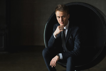 young businessman sitting in chair on grey background
