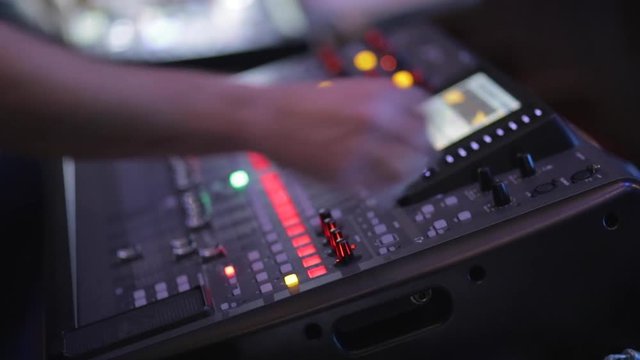 The man controls the mixer during a concert in the dark.