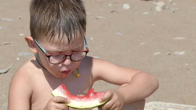 Boys eating watermelon on the beach. Slow motion