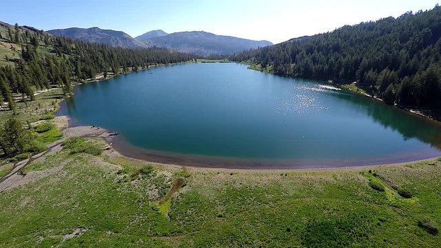 This video is about 4k Aerial View Highland Lakes Arnold California with sun reflecting off the calm water and mountains in the background