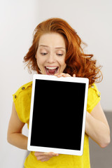 lachende frau zeigt ein tablet mit leerem bildschirm