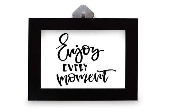 Enjoy every moment. Handwritten text. Modern calligraphy. Inspirational quote in black wooden frame