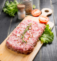 Minced pork uncooked with cutting board on wood background