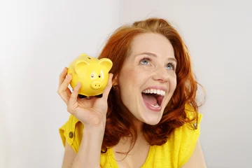 Foto op Plexiglas glückliche frau mit einem gelben sparschwein © contrastwerkstatt