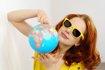 frau mit sonnenbrille zeigt einen globus