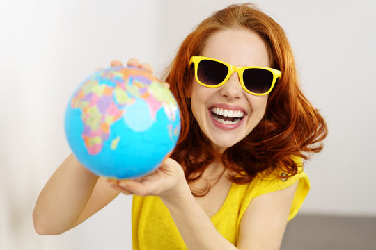 lachende frau mit sonnenbrille und globus