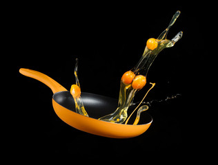 Fresh blended egs flying from a pan on black background