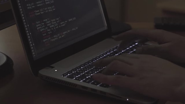 Programmer hands typing on the laptop in dark room