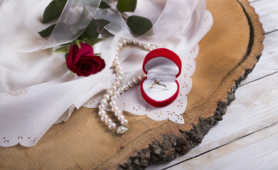 Marriage proposal with gold ring and red rose on wooden