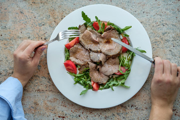 Healthy food. Salad from arugula, tomatoes and roast beef.
