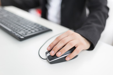 Frau bewegt Maus am Schreibtisch im Büro