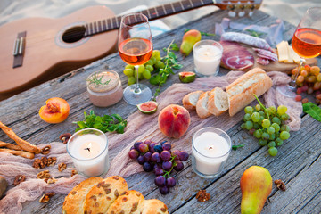 Picnic on the beach at sunset in boho style, food and drink concept