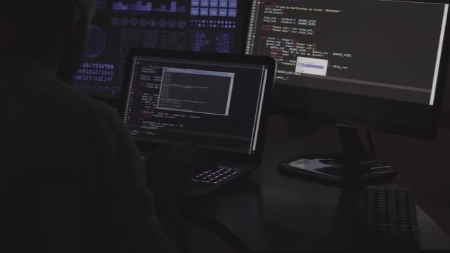 IT programmer is working on laptop in dark room