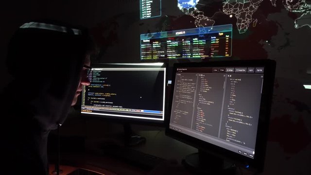 Young IT programmer prints the code on the computer in dark office room
