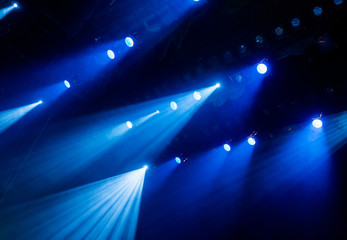 The blue light from the spotlights through the smoke in the theatre during the performance. Lighting equipment.