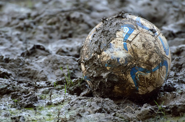 Soccer ball in clay in rainy season.