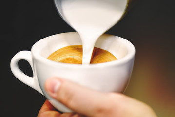Cup of coffee. Latte art made by barista focus in milk and coffee. Vintage color