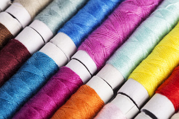 Multicolor sewing threads on wooden background