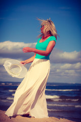 Fototapeta na wymiar Blonde woman wearing dress walking on beach