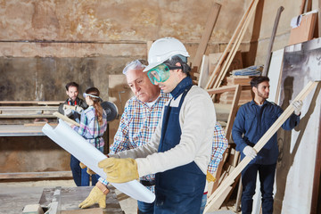 Schreiner Lehrling und Senior mit Bauplan