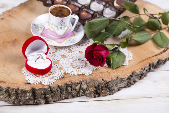 Marriage proposal with gold ring and red rose with Turkish coffee on wooden