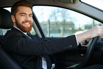 Side view of happy business man sitting at the wheel