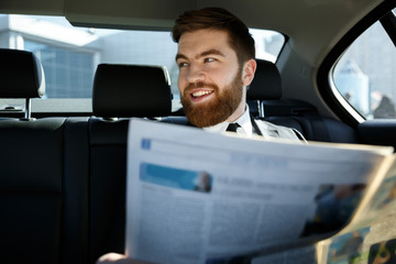 Happy bearded man sitting with newspaper