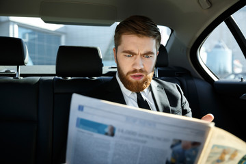Incomprehensible business man reading newspaper