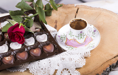 Turkish coffee with red rose and heart shaped chocolates on the wooden table