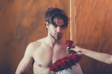 bearded muscular man with sexy body holds red rose box