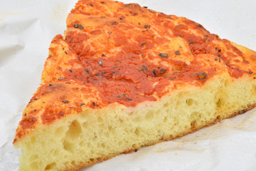 A slice of Italian homemade thick pizza with tomatoes sauce and oregano, also called “red focaccia”: it is typical of North Italy.