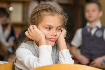 Girl bored at school sitting at a desk on the reverse