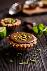 Tartlets with chocolate, pistachios and lime peel