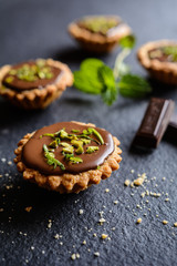 Tartlets with chocolate, pistachios and lime peel