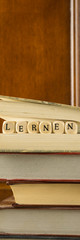 Ein Stapel Bücher, vertikales Banner mit dem Wort Lernen zwischen den Buchseiten