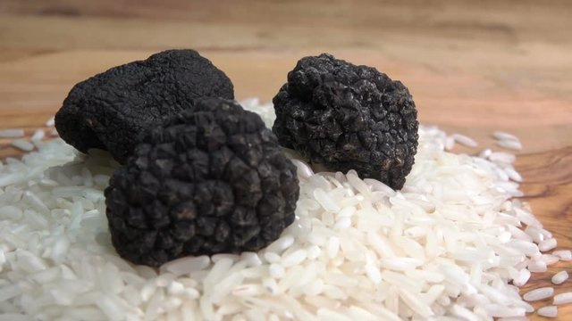 Close-up of black truffles lying on rice on the wooden board