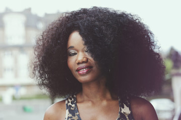 portrait jeune femme noire avec grande coiffure afro cheveux bouclés en ville en été