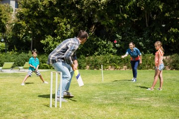 Happy family playing cricket in park