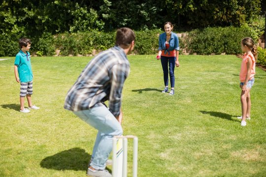 Happy Family Playing Cricket In Park