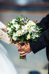 Man's and female hand holds a wedding bouquet