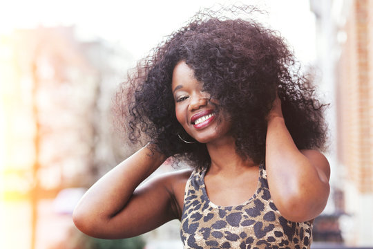 portrait jeune femme noire avec grande coiffure afro cheveux bouclés en ville en été