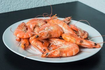 king prawns in a white plate on a black background
