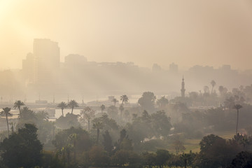 Sunrise in central Cairo, the first rays of sun piercing through the morning mist.