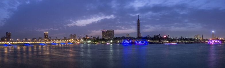 Panoramic view of Cairo city center at twilight, the Kasr El Nile Bridge and the island of Zamalek with its colorful boats on the Nile river. © fcerez